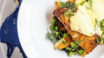 Um prato branco com carne, legumes verdes e um molho cremoso.