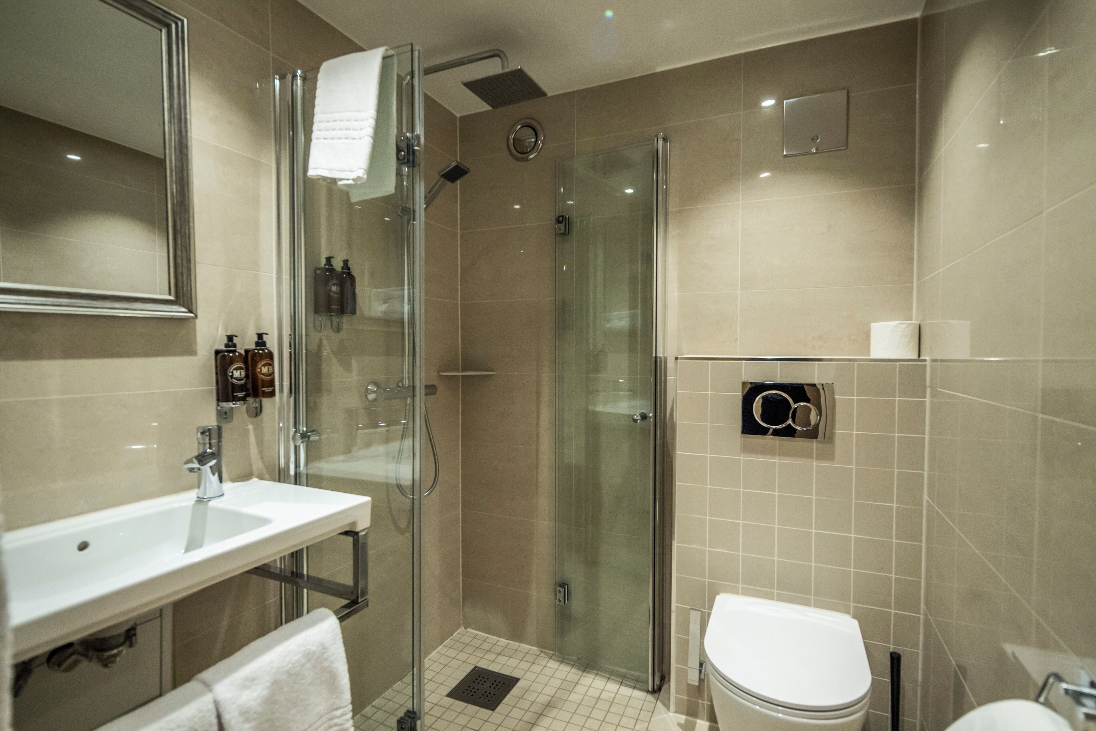 A modern bathroom with a glass-enclosed shower, a white sink, and a toilet.