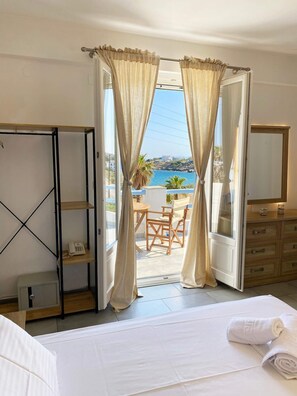 Una habitación de hotel con una cama, un escritorio, una silla y vista al mar.