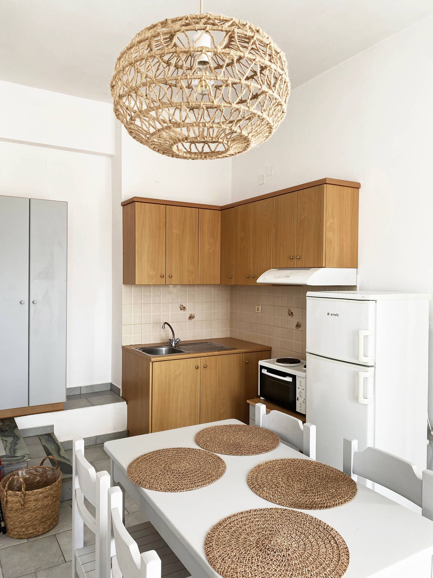 Una cocina moderna con armarios de madera, encimera blanca, horno empotrado y refrigerador blanco.