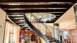 Un amplio vestíbulo con una escalera curva, una zona de estar con un sofá y plantas en macetas.