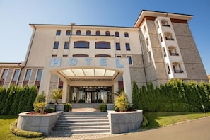 A hotel with a prominent entrance, a covered area with steps, and a tall building with balconies. - The Vineyards Spa & Resort (Pomorie)