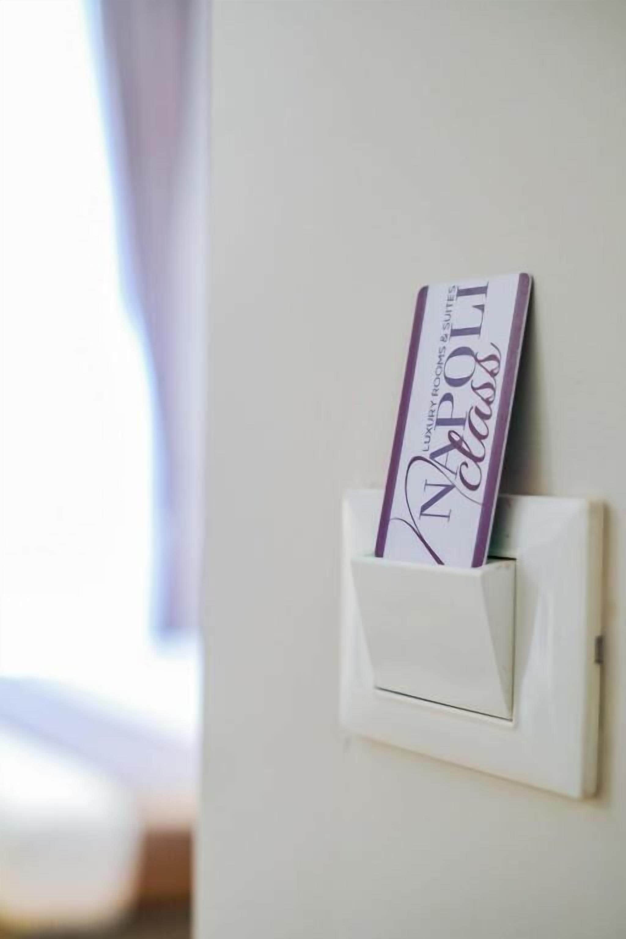 A white wall-mounted light switch with a card inserted into it.