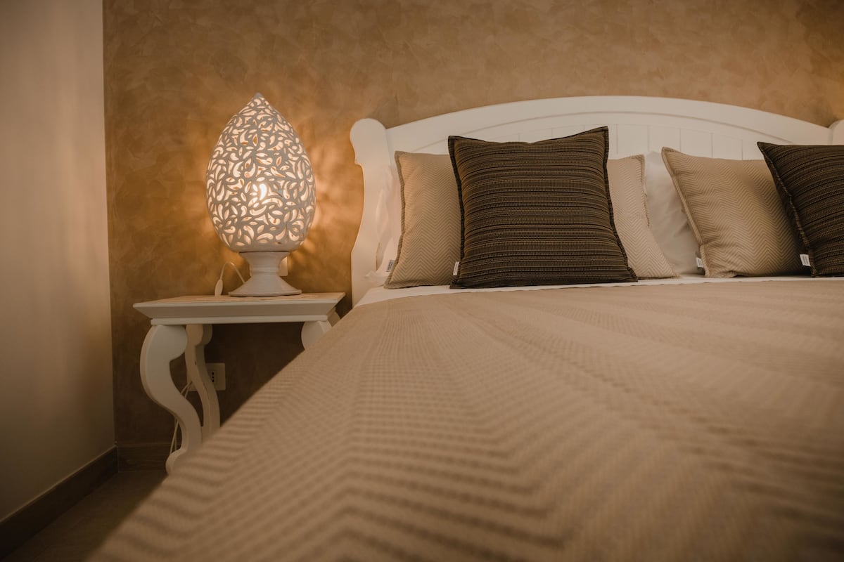 A neatly made bed with a textured blanket, a white headboard, and two pillows.