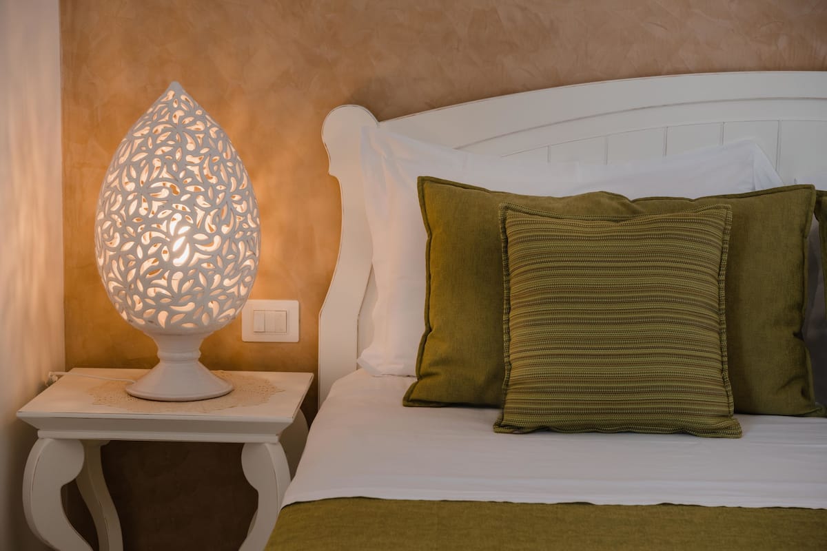 A neatly made bed with a white headboard and two green pillows.