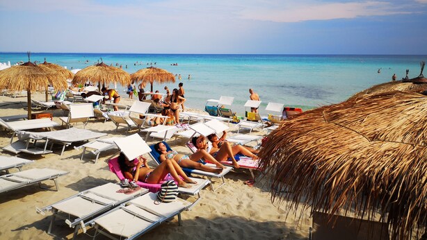 A beach with sun loungers, thatched umbrellas, and a clear view of the ocean. - Tenuta Flora Maria (Leverano)