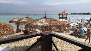 A beach with thatched umbrellas, lounge chairs, and a wooden structure. - Tenuta Flora Maria (Leverano)
