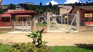 Un'area recintata con un cancello, un piccolo edificio con tetto rosso e un cartello in spagnolo.