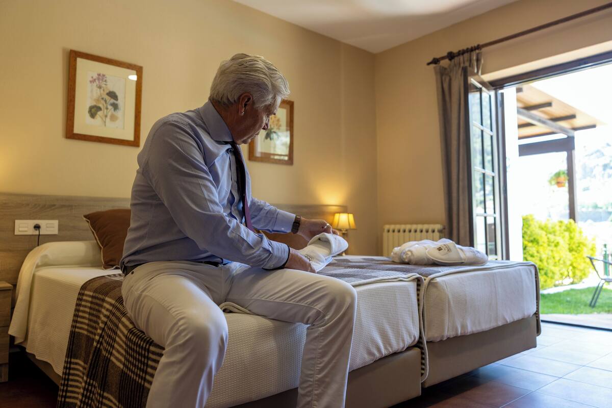 Una habitación de hotel con una cama, una mesita de noche y una ventana con cortinas.
