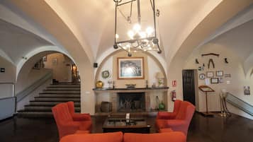A spacious living room with a fireplace, a staircase, and a chandelier.