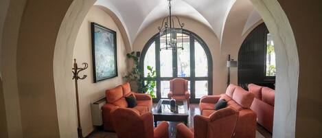 A room with a high arched ceiling, a fireplace, and a seating area with sofas and armchairs.