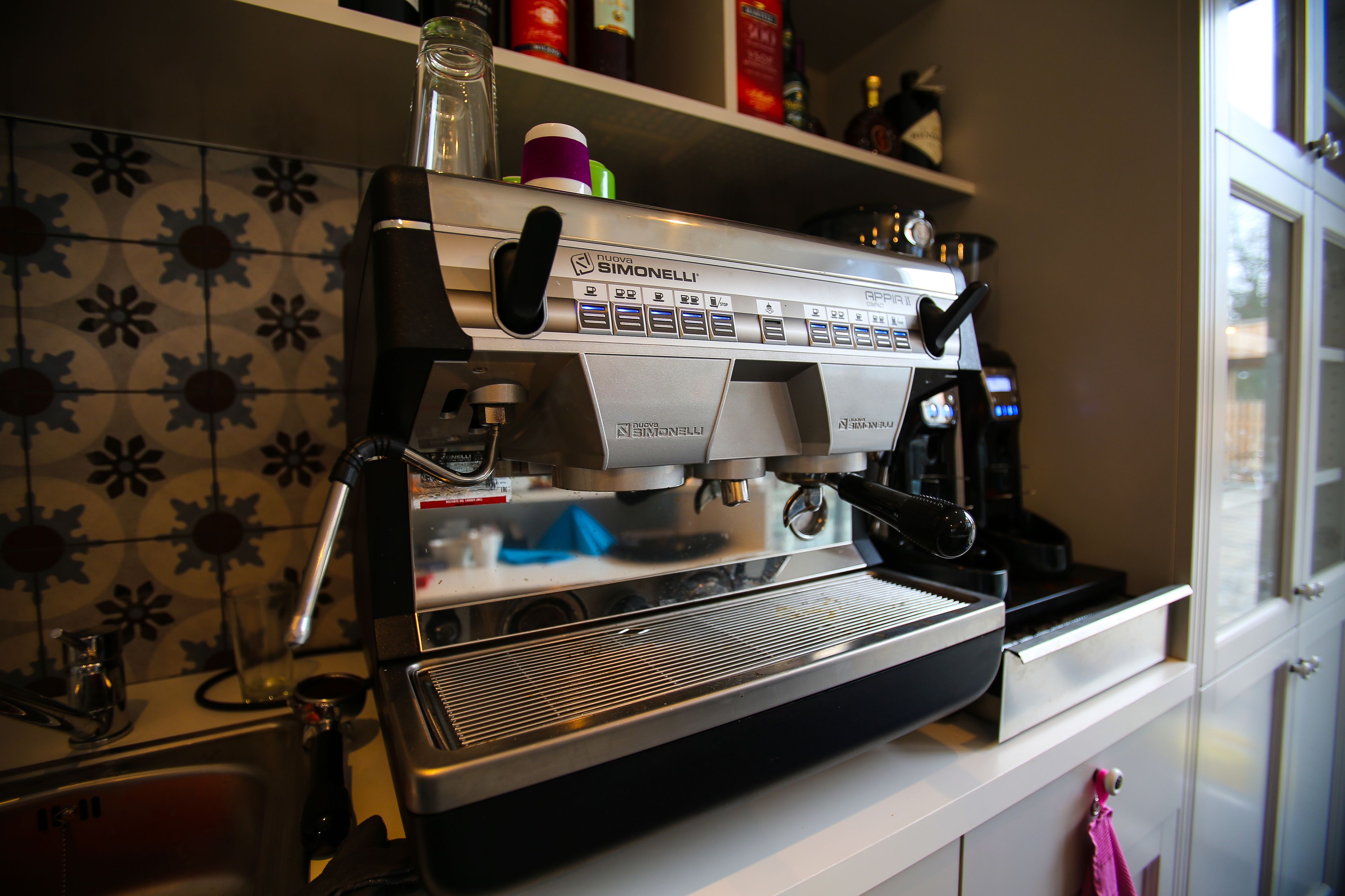 A commercial espresso machine with a digital display, a milk frothing station, and a coffee grinder.