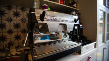 A commercial espresso machine with a digital display, a milk frothing station, and a coffee grinder.