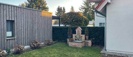 Una casa moderna con fachada de madera, un elemento decorativo de piedra en el jardín y un césped bien cuidado.