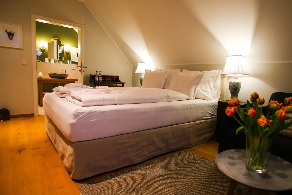 Une chambre à coucher avec un lit, une table de chevet, une lampe et un vase rempli de fleurs.