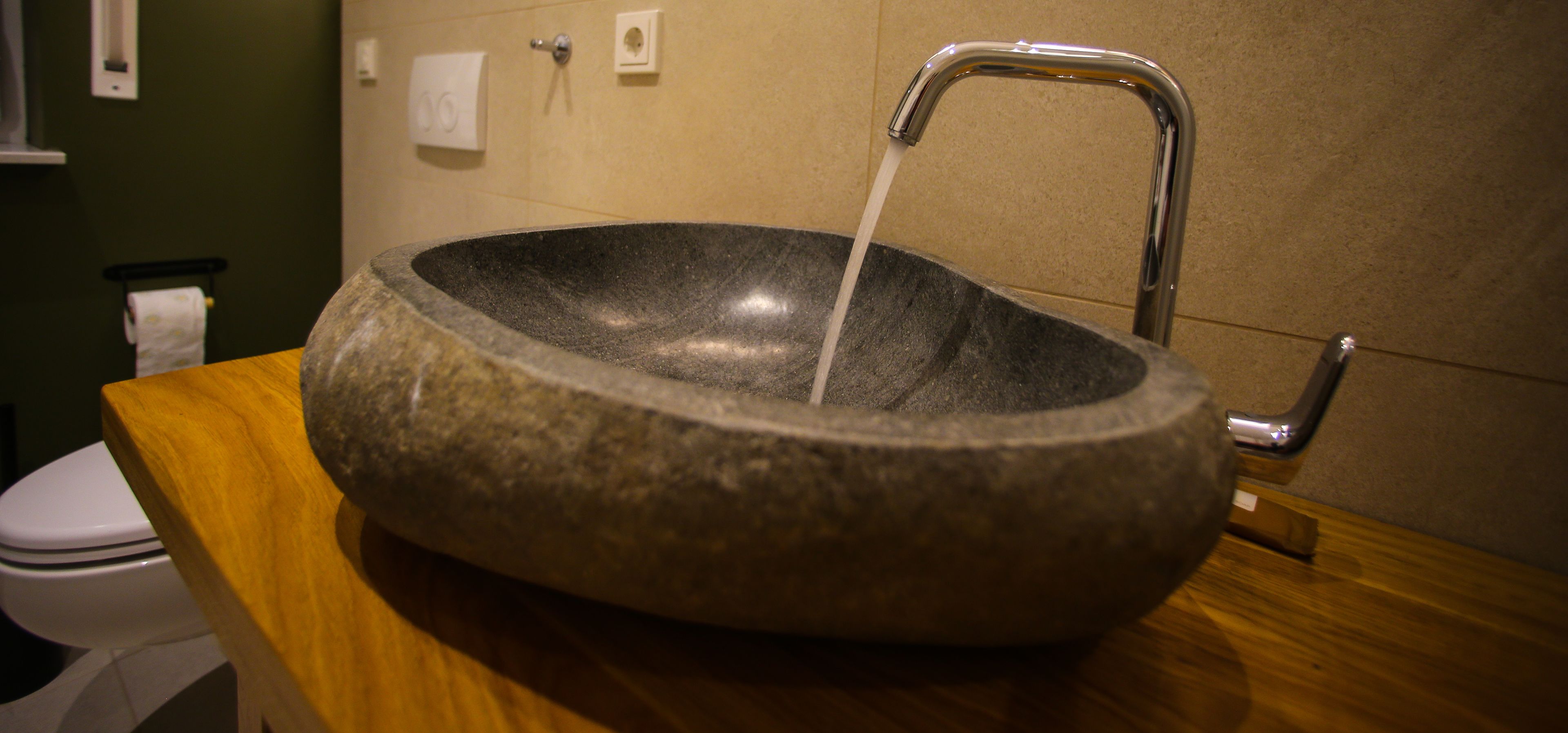 A stone sink with running water in a bathroom.
