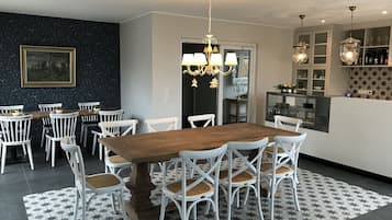 Un comedor con mesa de madera y sillas blancas, una araña y suelo estampado.