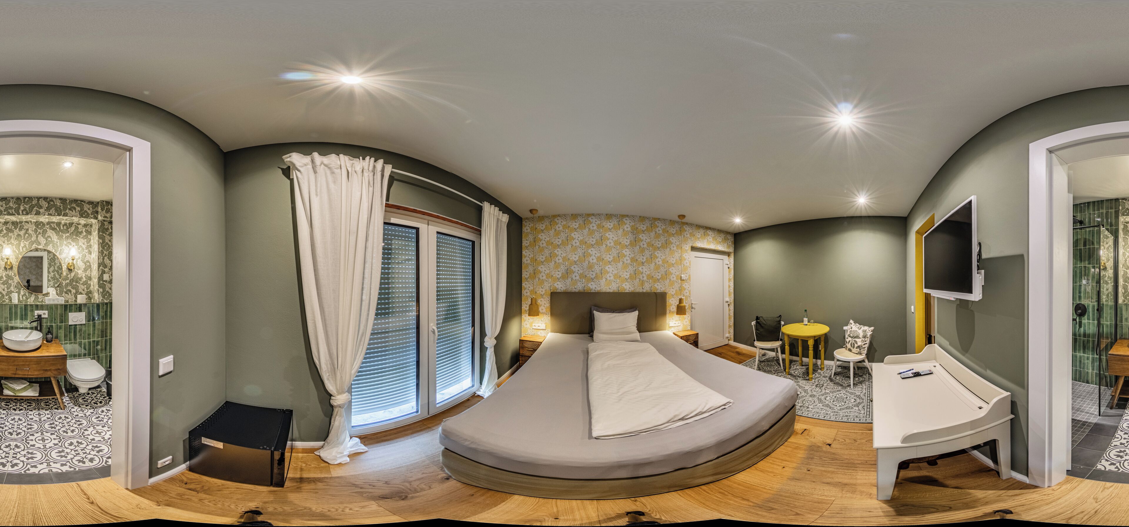 Una camera da letto moderna con un letto a forma di ferro di cavallo, una scrivania, una sedia e una TV.