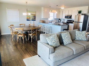 A modern kitchen with white cabinets, stainless steel appliances, and a dining area with a round table and wicker chairs.