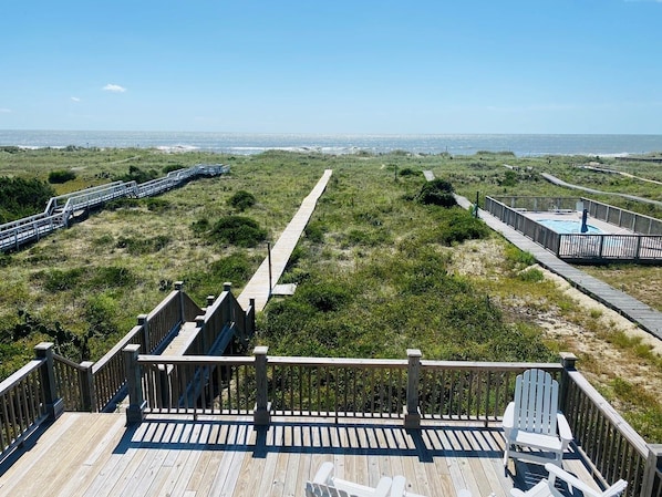 A wooden deck with a view of the beach and ocean.