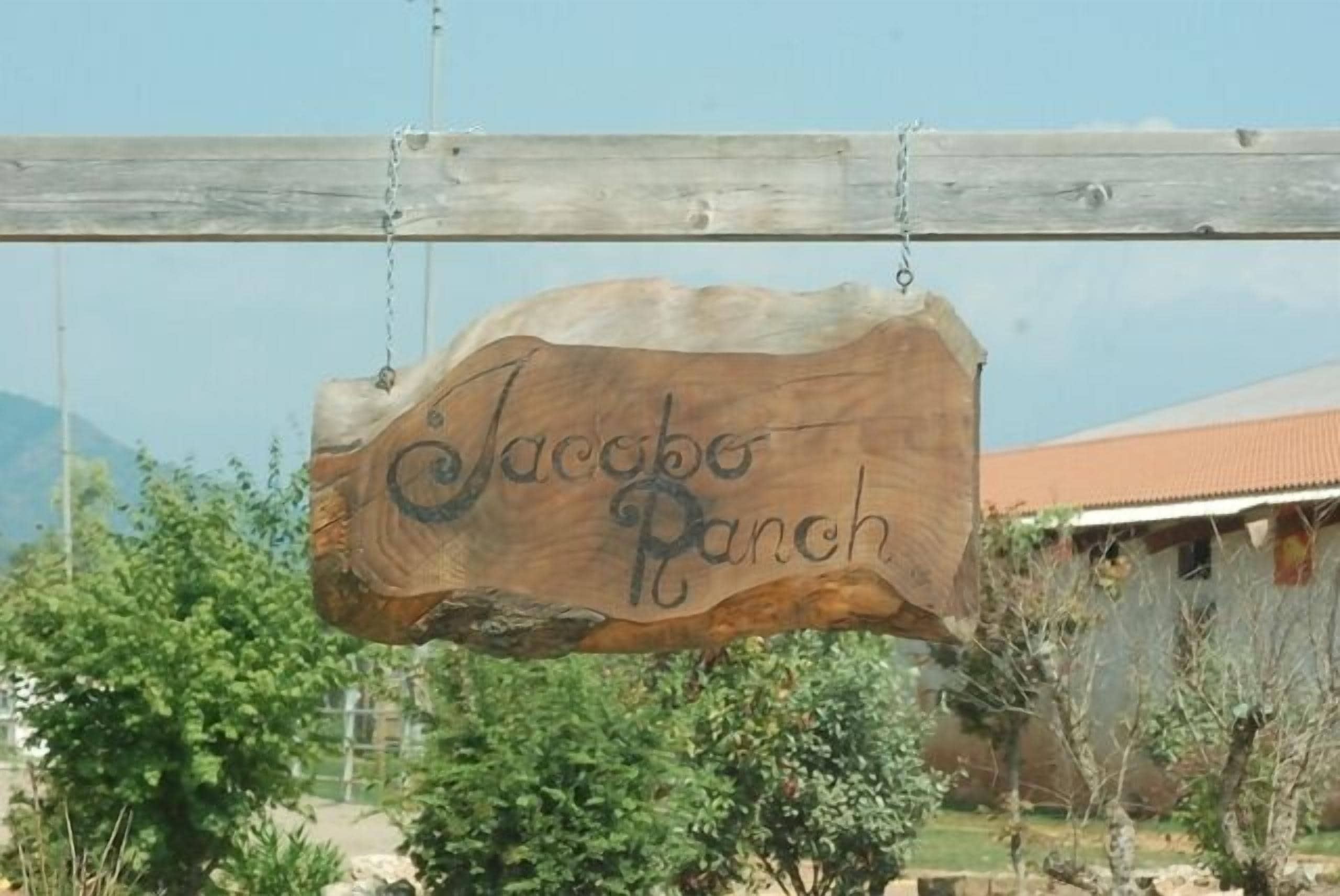 Un cartello di legno con la scritta 'Jacobe Ranch' appeso a una trave.