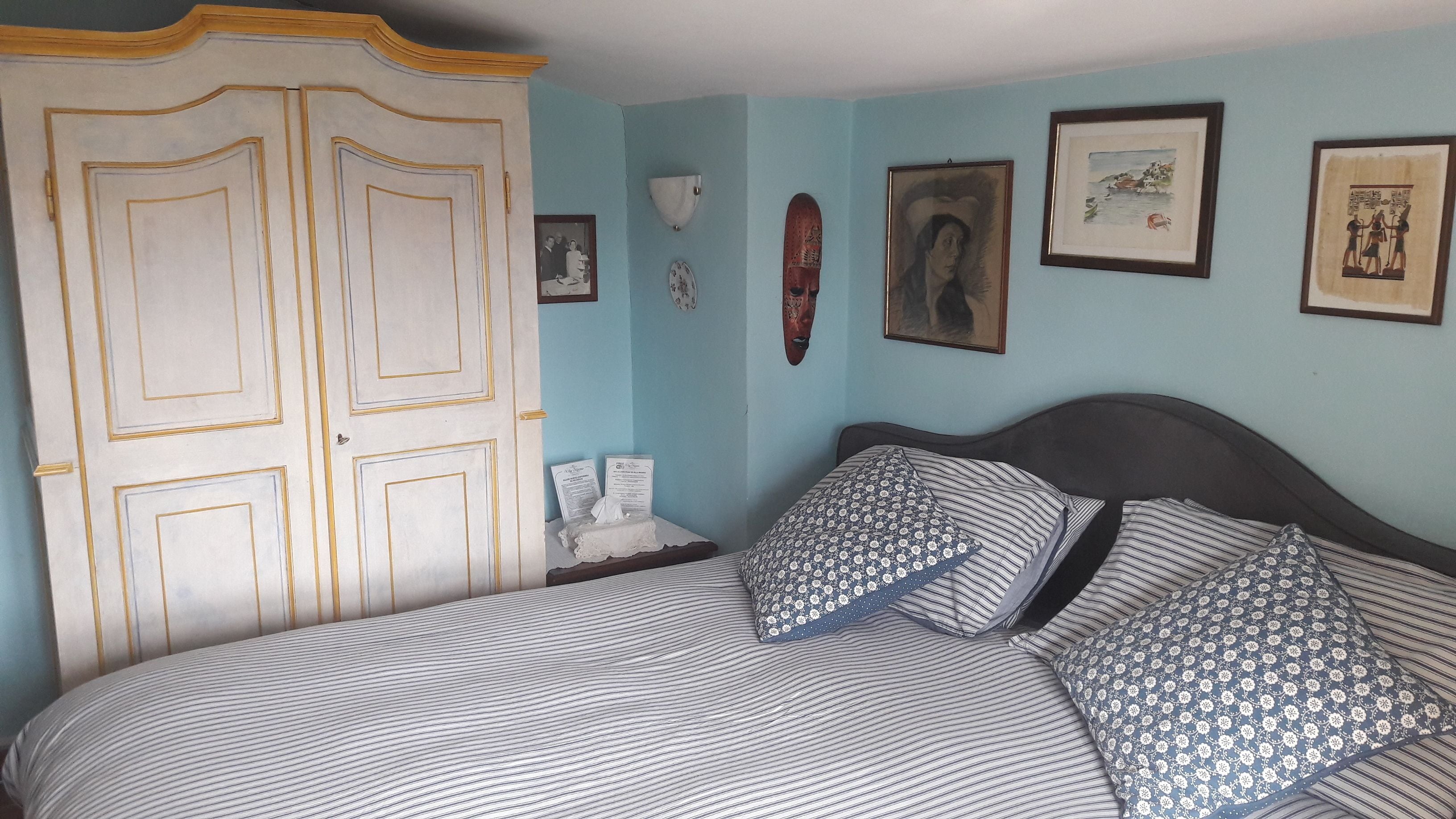 Ein Schlafzimmer mit einem Bett, einem Kleiderschrank und mehreren gerahmten Bildern an der Wand.