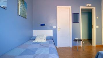 A bedroom with a bed, a nightstand, a chair, and a door leading to another room.