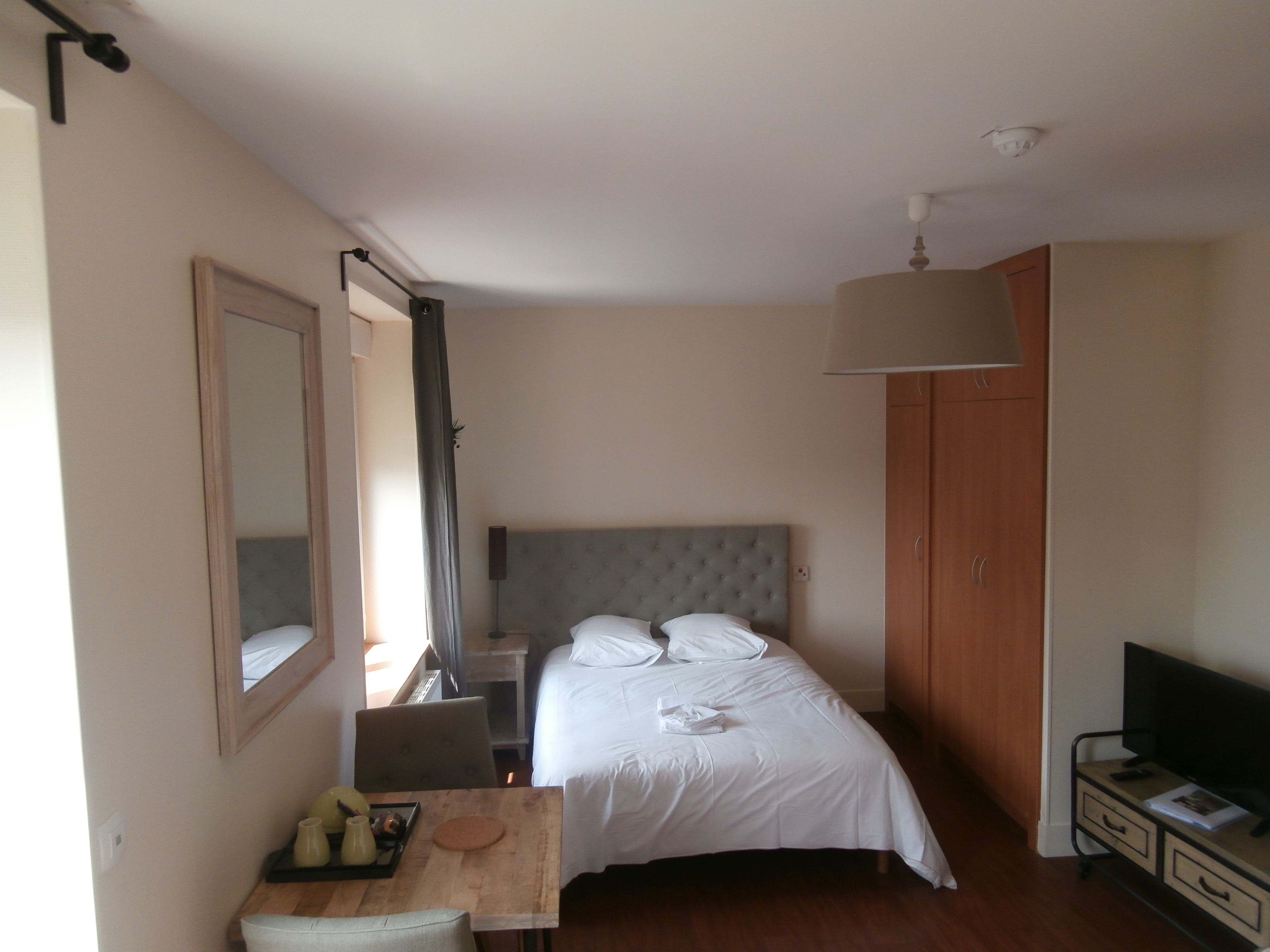 Une chambre à coucher comprenant un lit, un bureau avec une chaise, une télévision et une armoire.