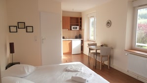 Een slaapkamer met een bed, een bureau en uitzicht op de keuken.