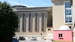 Een gebouw met een groot centraal raam, een koepel en een roze constructie.