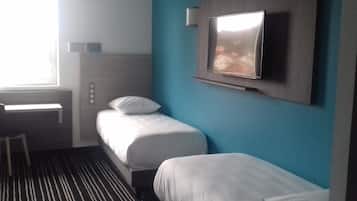A hotel room with a bed, a desk, and a television mounted on the wall.
