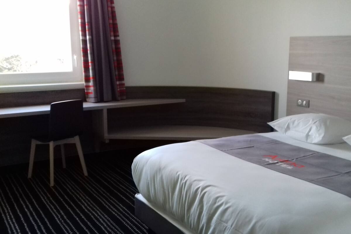 Ein Hotelzimmer mit Bett, Schreibtisch und Stuhl.
