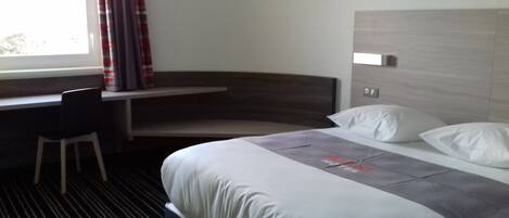 Una habitación de hotel con una cama, un escritorio y una silla.