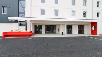 A modern building with a flat roof, large windows, and a red accent wall.