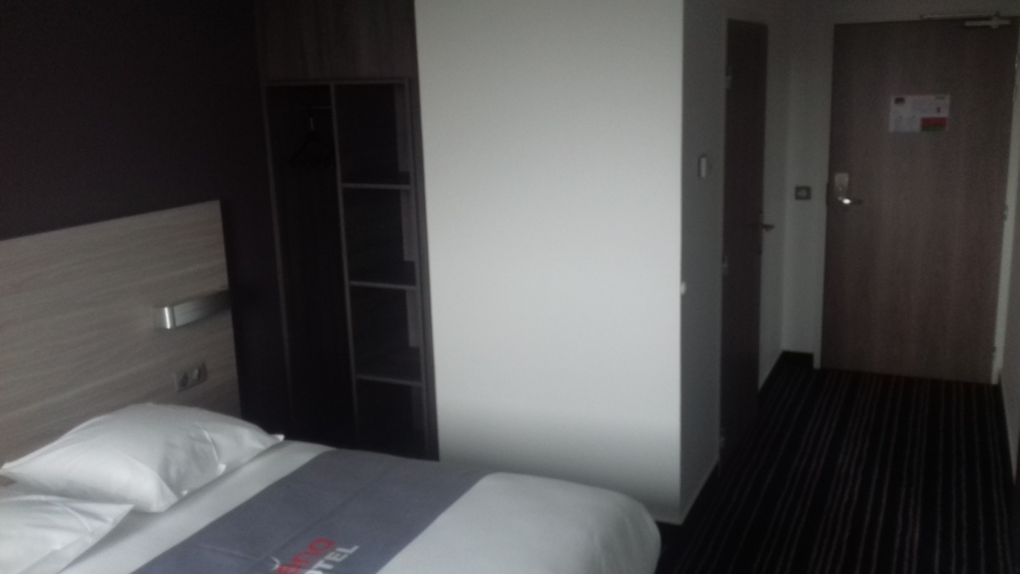 Una habitación de hotel con una cama, un armario y una puerta que da a otra habitación.