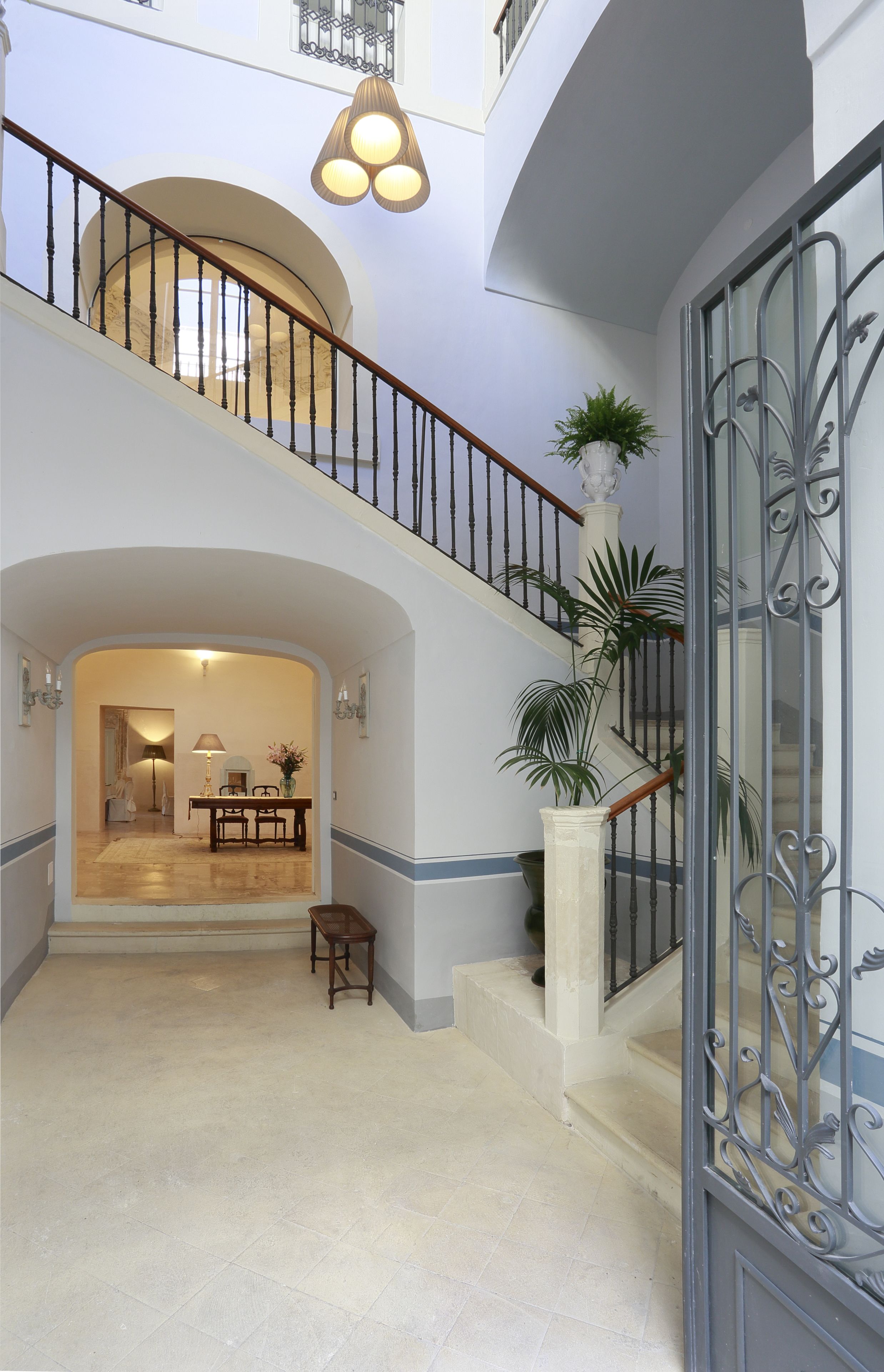 Un intérieur spacieux comprenant un escalier, un coin repas et une grande plante en pot.