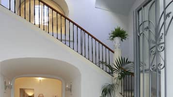 Un intérieur spacieux comprenant un escalier, un coin repas et une grande plante en pot.