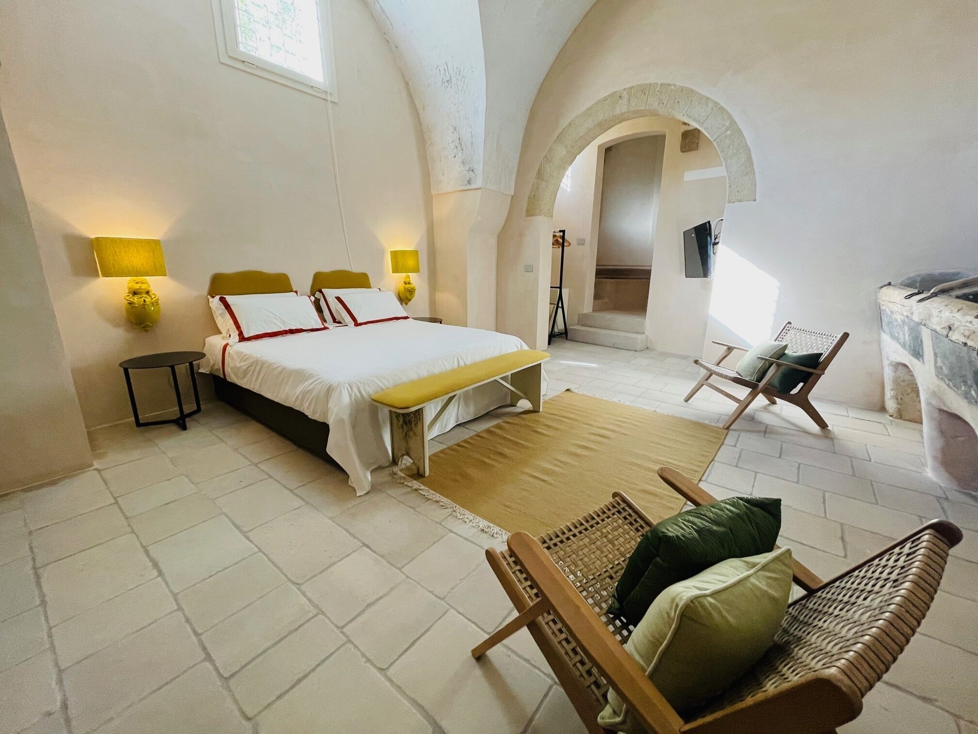 A bedroom with a bed, bedside tables, a chair, and a stone fireplace.