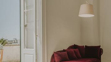 A red sofa in a room with a patterned floor, a white door, and a hanging light fixture.