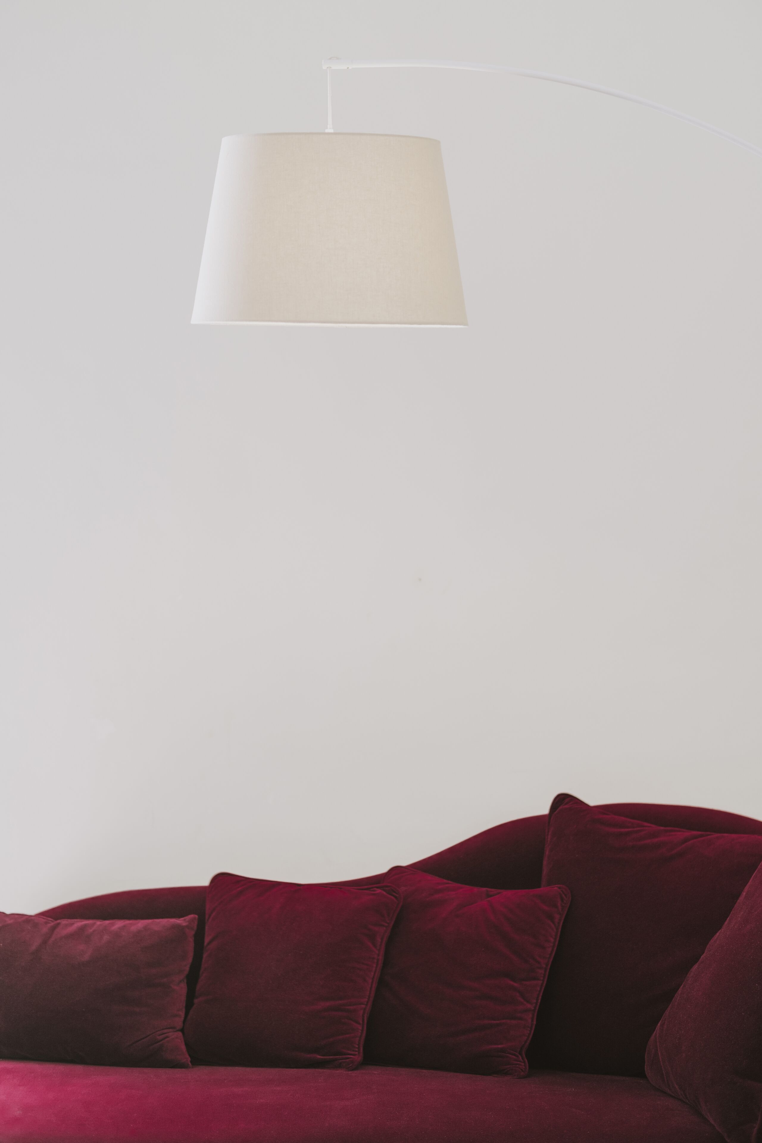 Un canapé en velours rouge avec une lampe blanche.