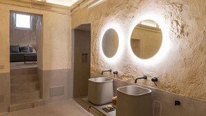 A bathroom with two sinks, a bench, and a large mirror. - Relais Monastero Santa Teresa (Nardò)