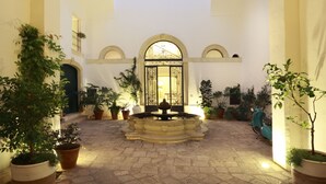 A courtyard with a fountain, potted plants, and a scooter. - Relais Monastero Santa Teresa (Nardò)