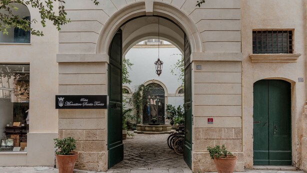 An entrance with an archway, a sign for 'Monastero Santo Teresa', and a green door. - Relais Monastero Santa Teresa (Nardò)