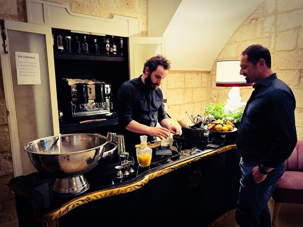 A kitchen with a large metal bowl, a coffee machine, and a counter with fruits and a bottle.