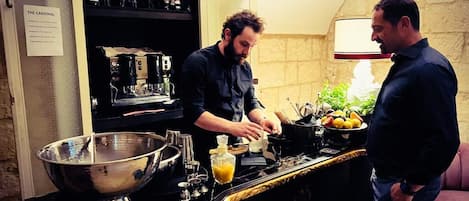 A kitchen with a large metal bowl, a coffee machine, and a counter with fruits and a bottle.