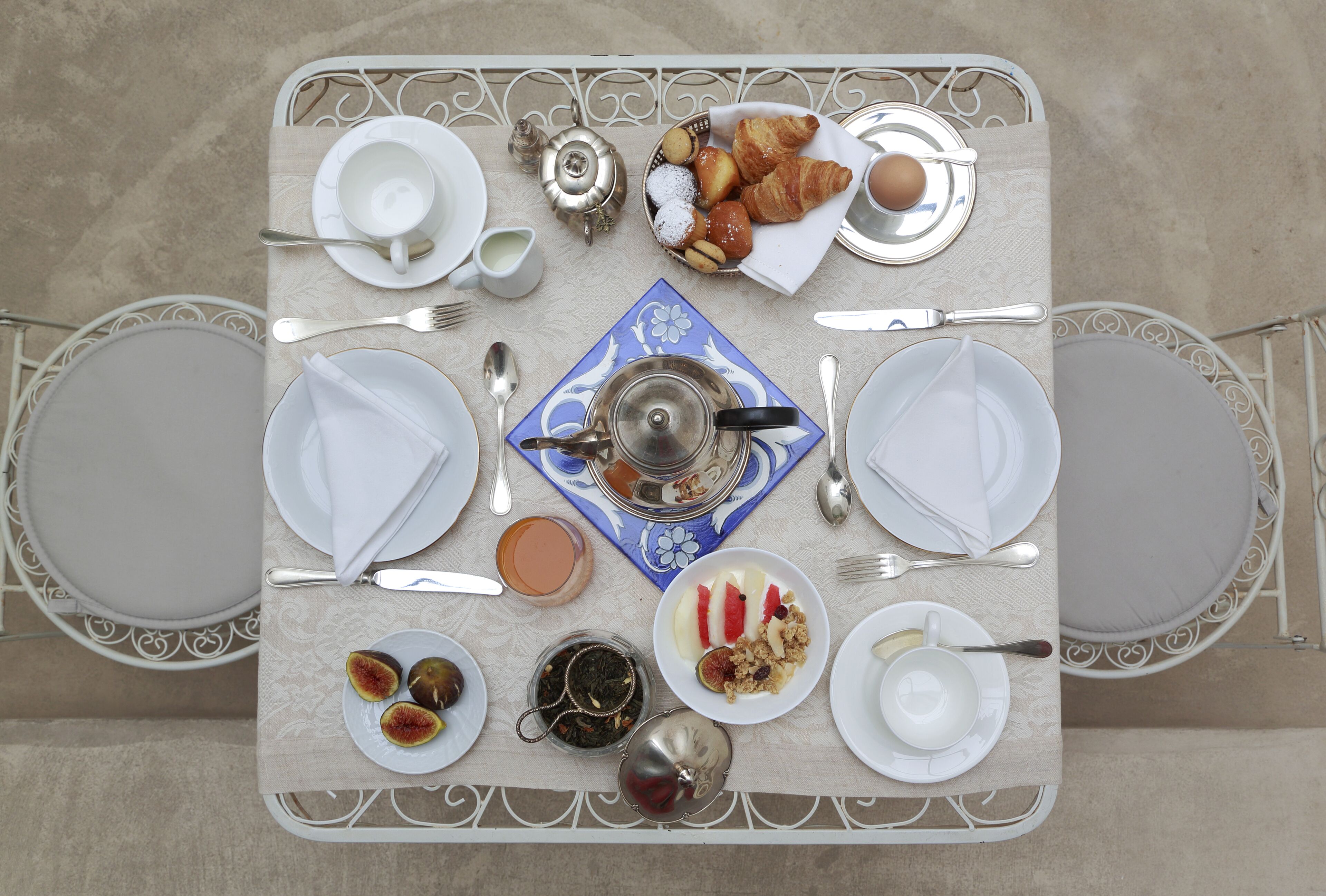 A table set for two with plates, cutlery, and a teapot.