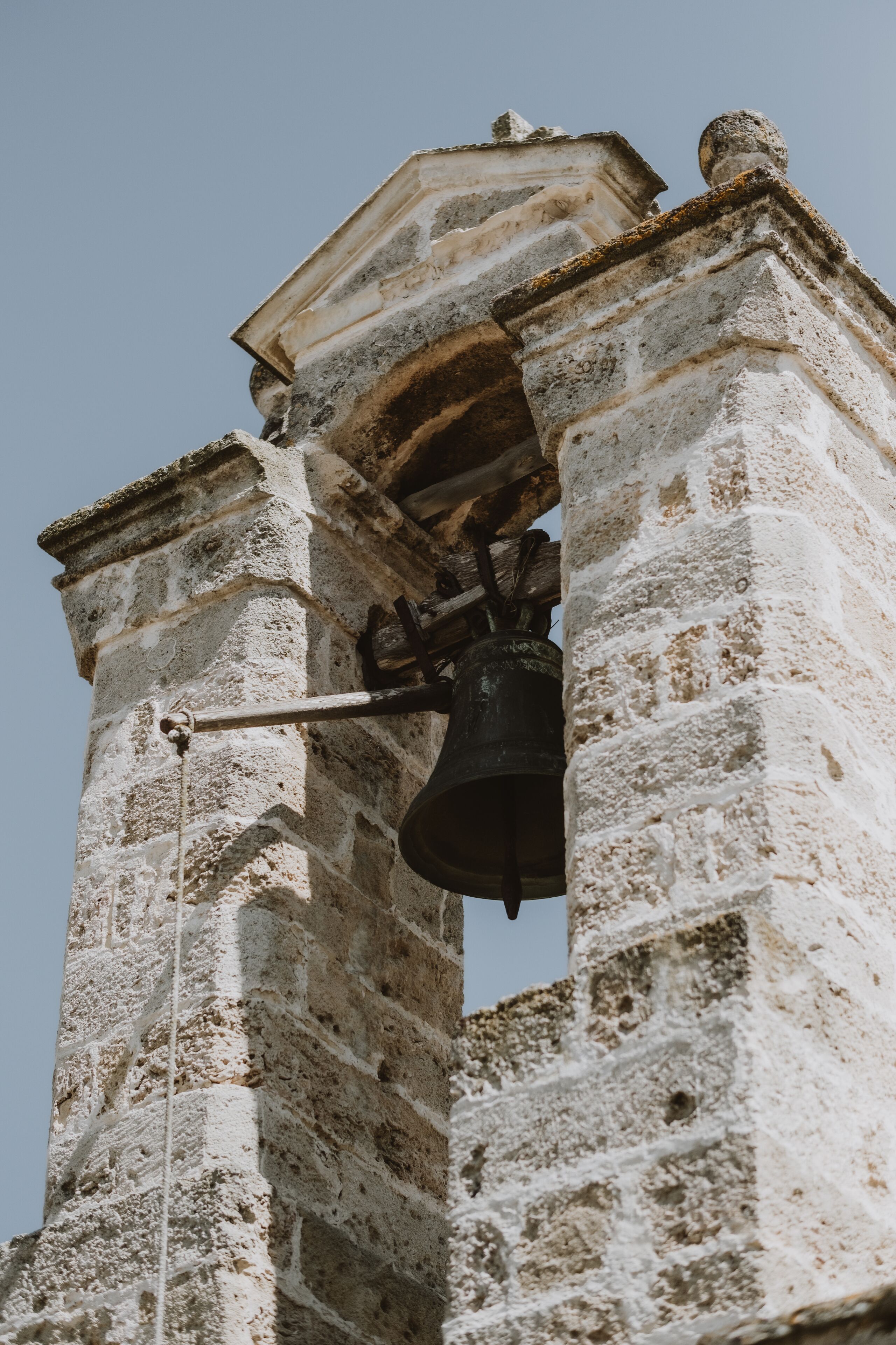 Un campanario con una campana colgando de una cuerda.