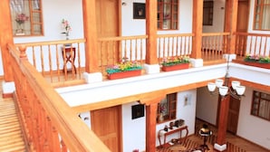 Un balcón de madera de varios niveles con barandillas, jardineras y un candelabro.