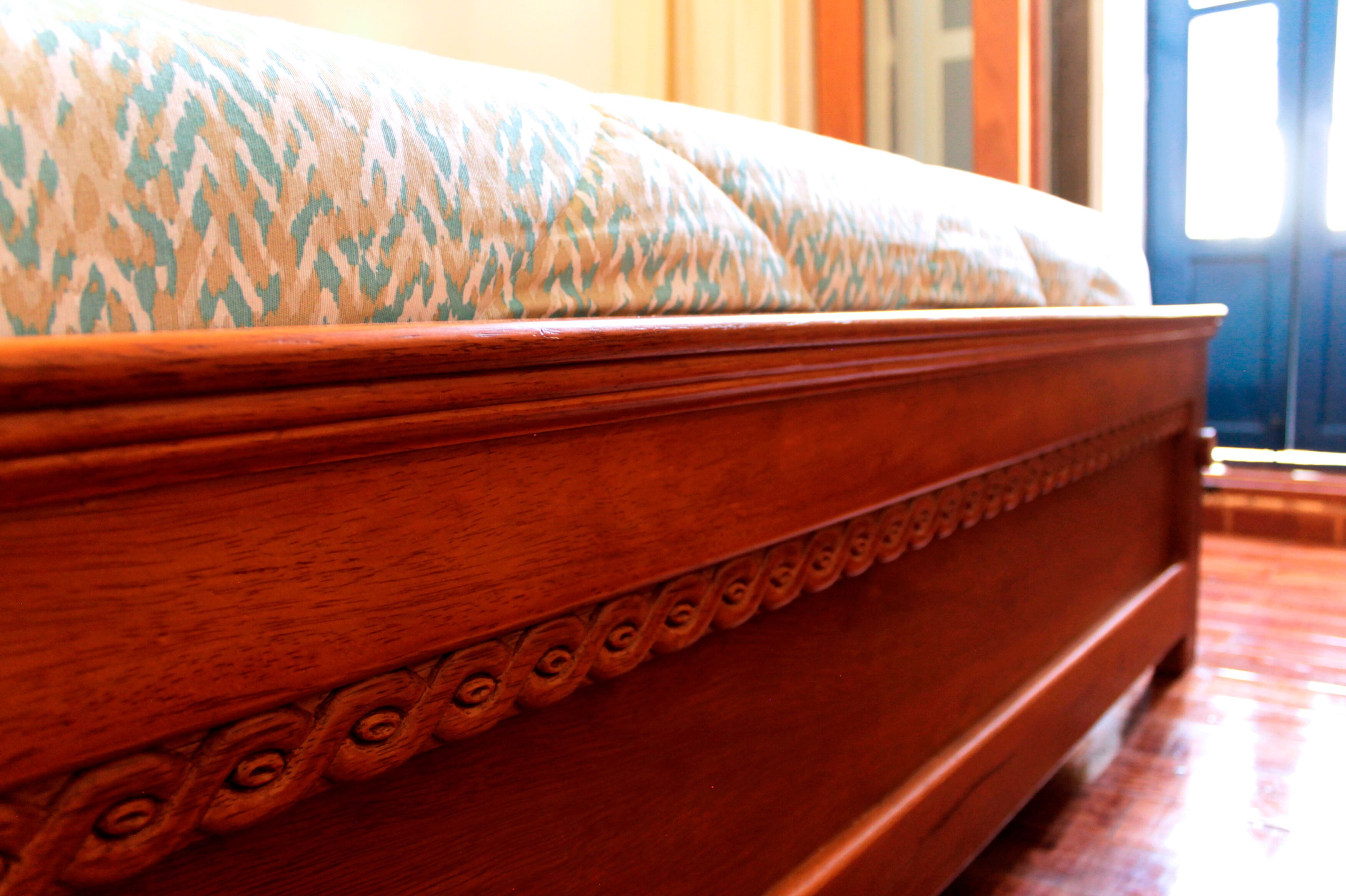 A wooden bed with a patterned headboard and a decorative edge.