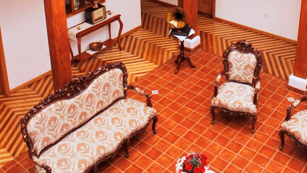 Un interior espacioso con techo alto, barandillas de balcón de madera y un candelabro.